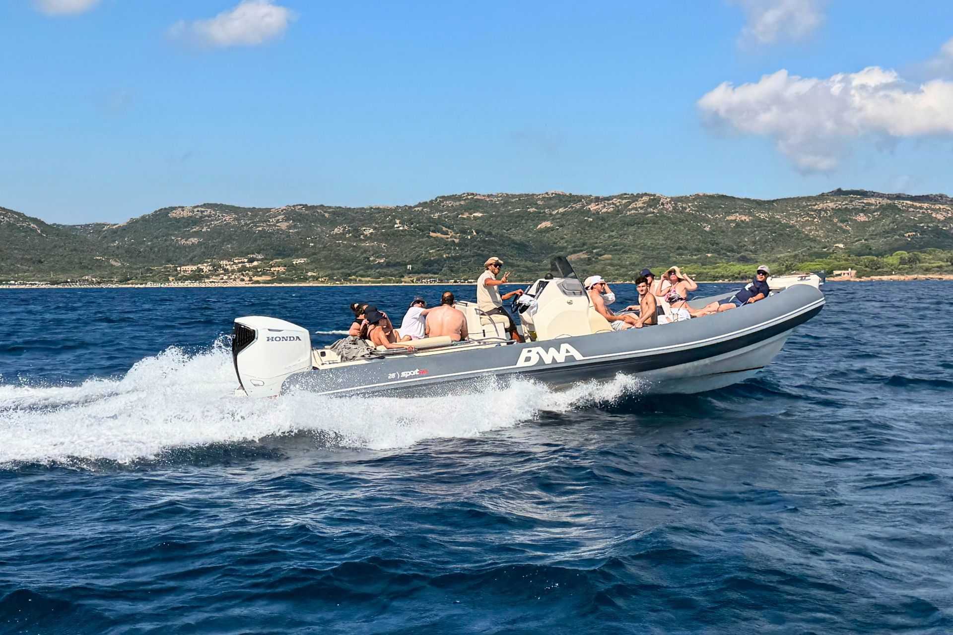 Eine Gruppe von Menschen in einem Beiboot, die zum Archipel von La Maddalena reist, mit atemberaubenden Landschaften im Hintergrund