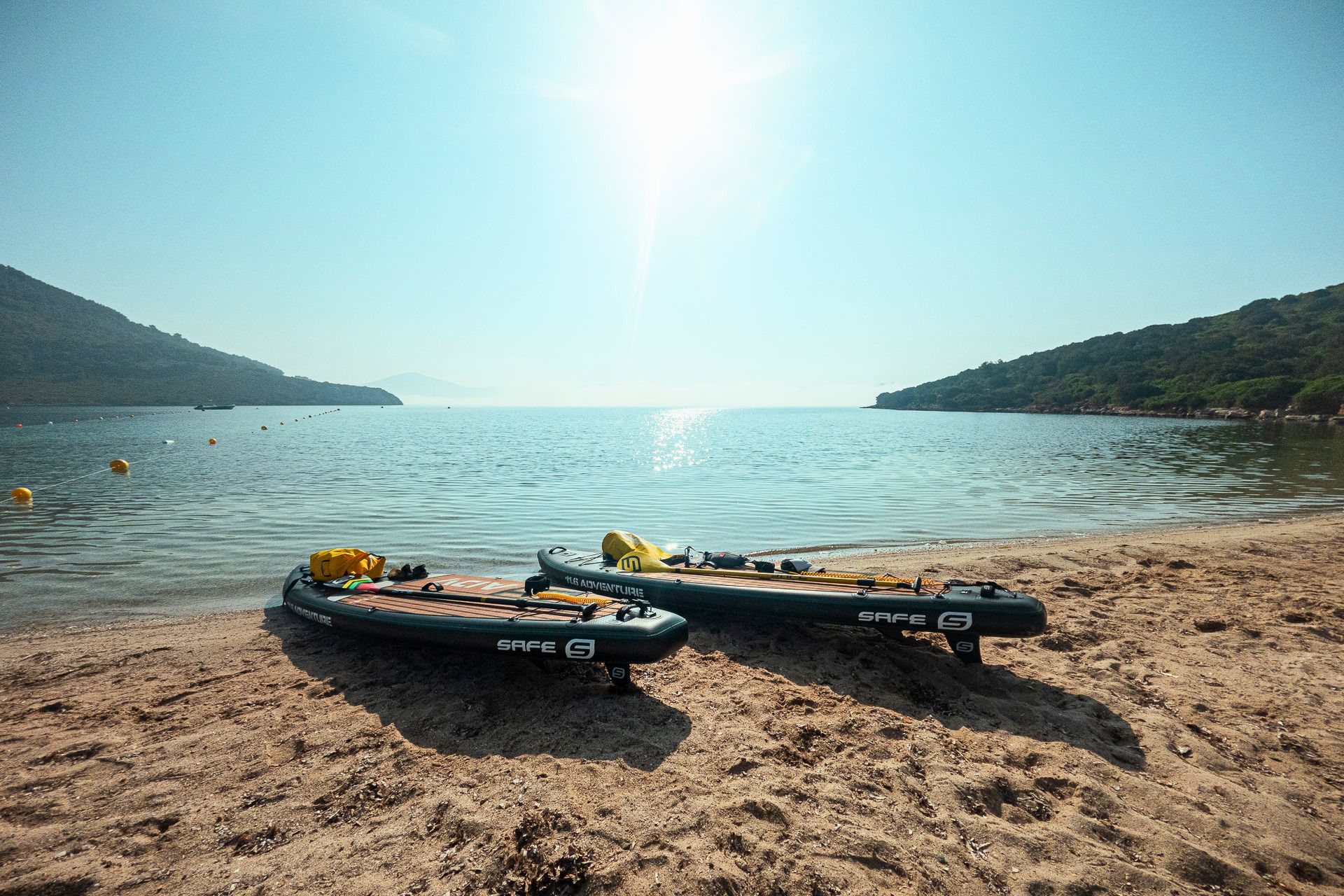 Deux planches de SUP abandonnées sur le sable d'une plage avec la mer calme en arrière-plan