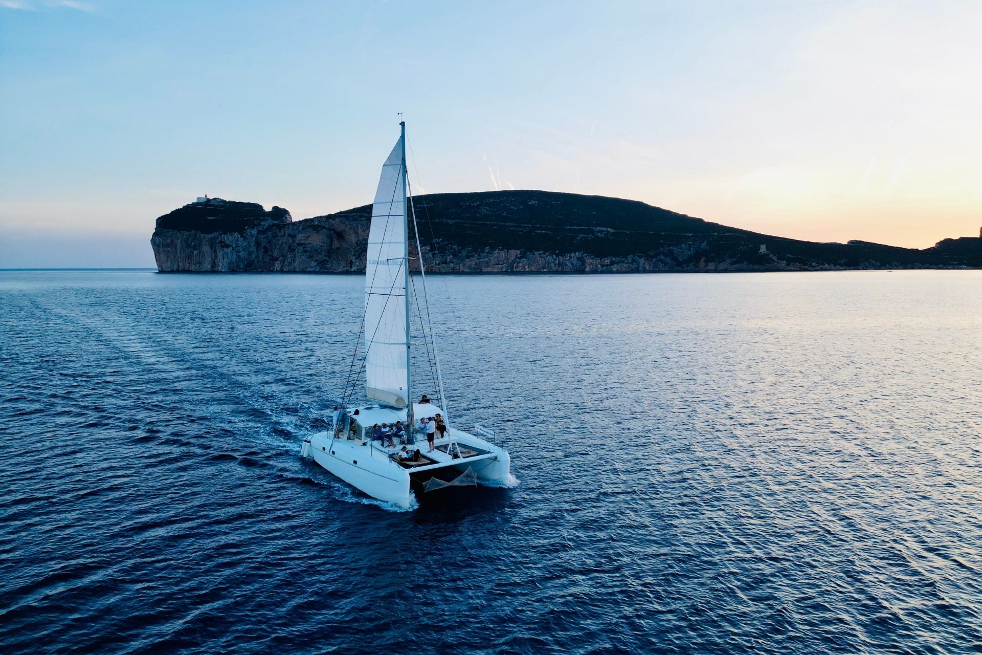 Navegación en catamarán por el mar al atardecer con personas a bordo