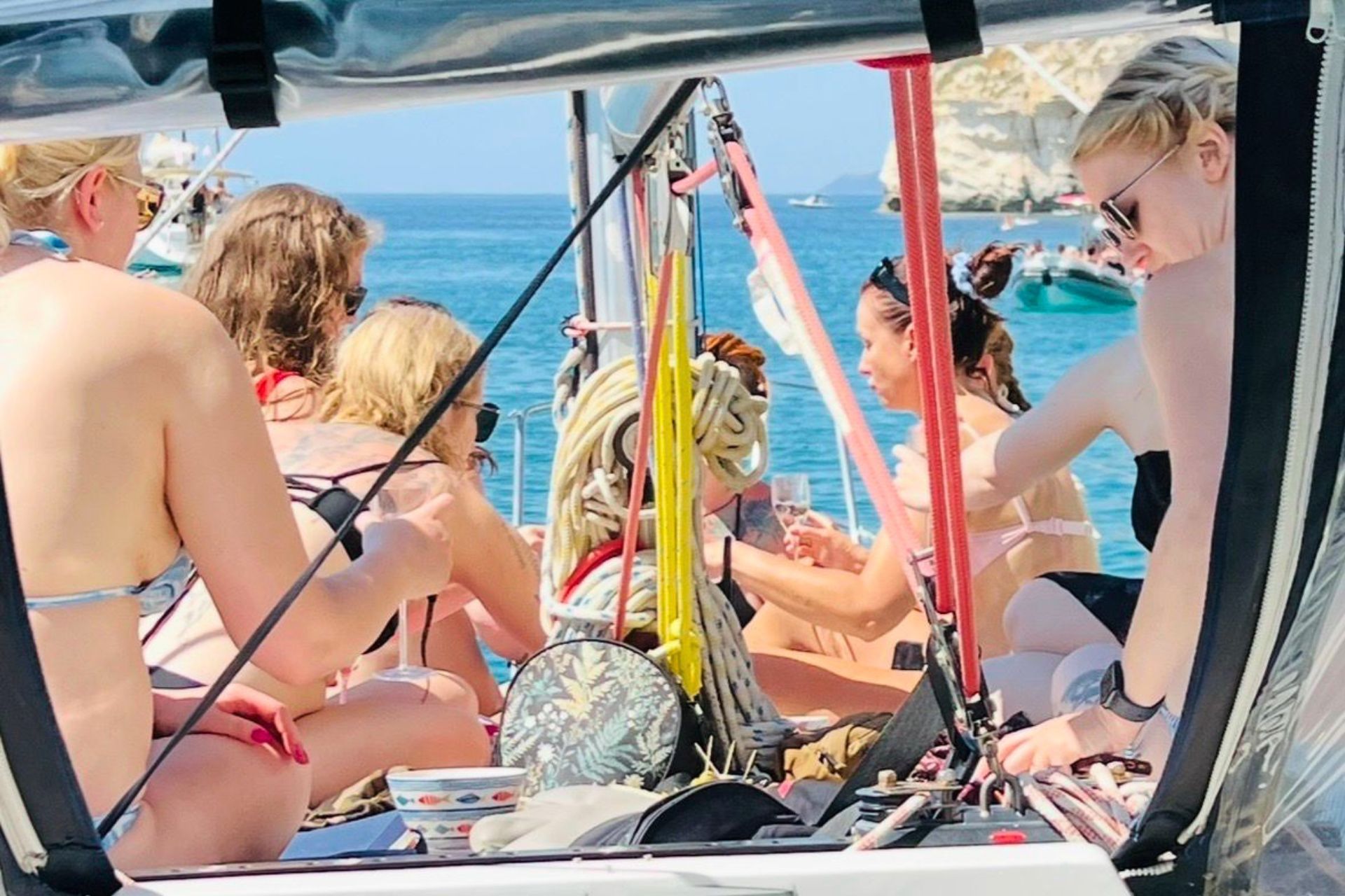 A group of women in swimsuits enjoy a sailing tour with an aperitif and stops in the coves of the Golfo degli Angeli