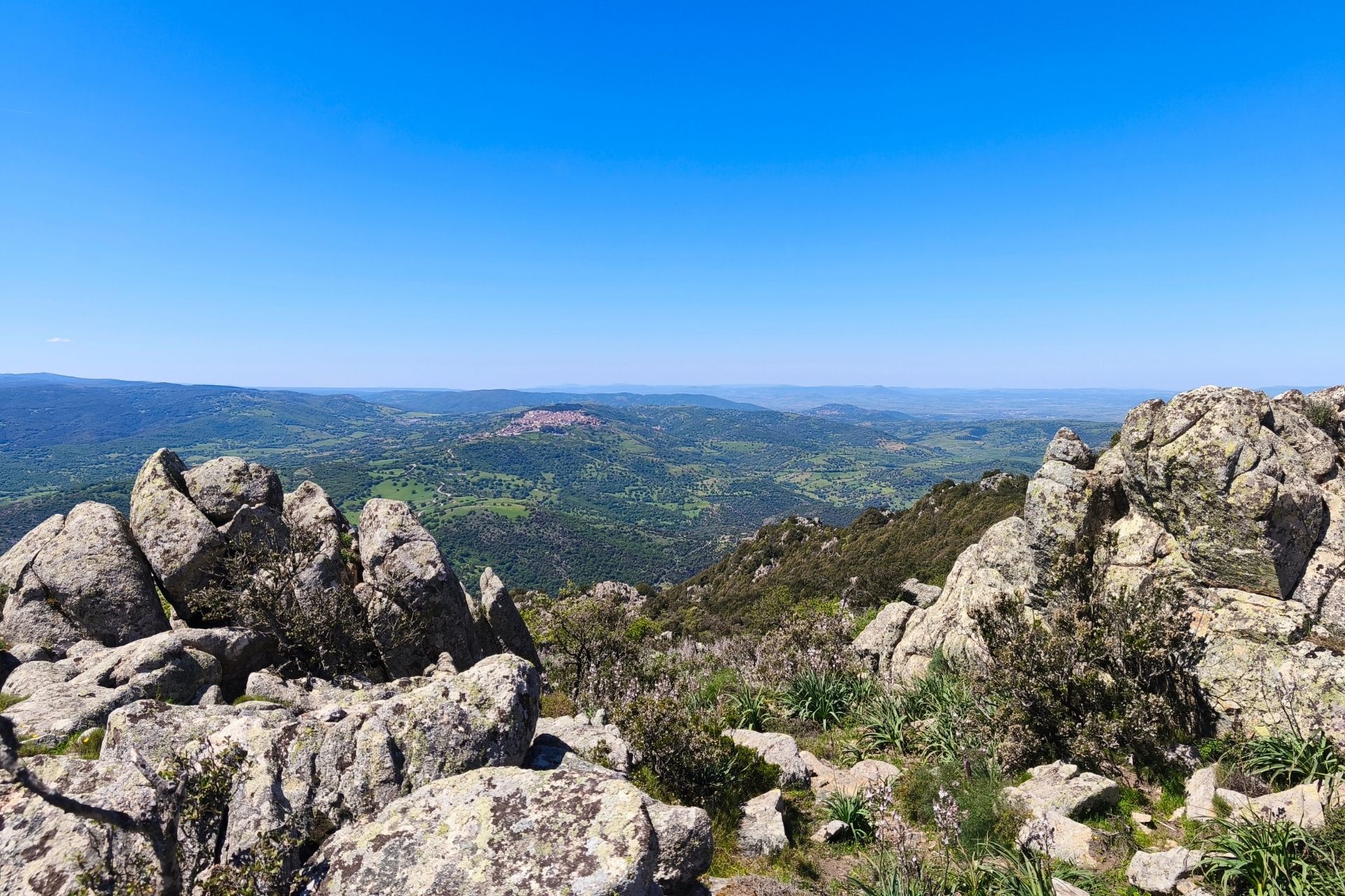 Vista panorámica desde una montaña con rocas y vegetación exuberante, típica de un paisaje natural de Cerdeña