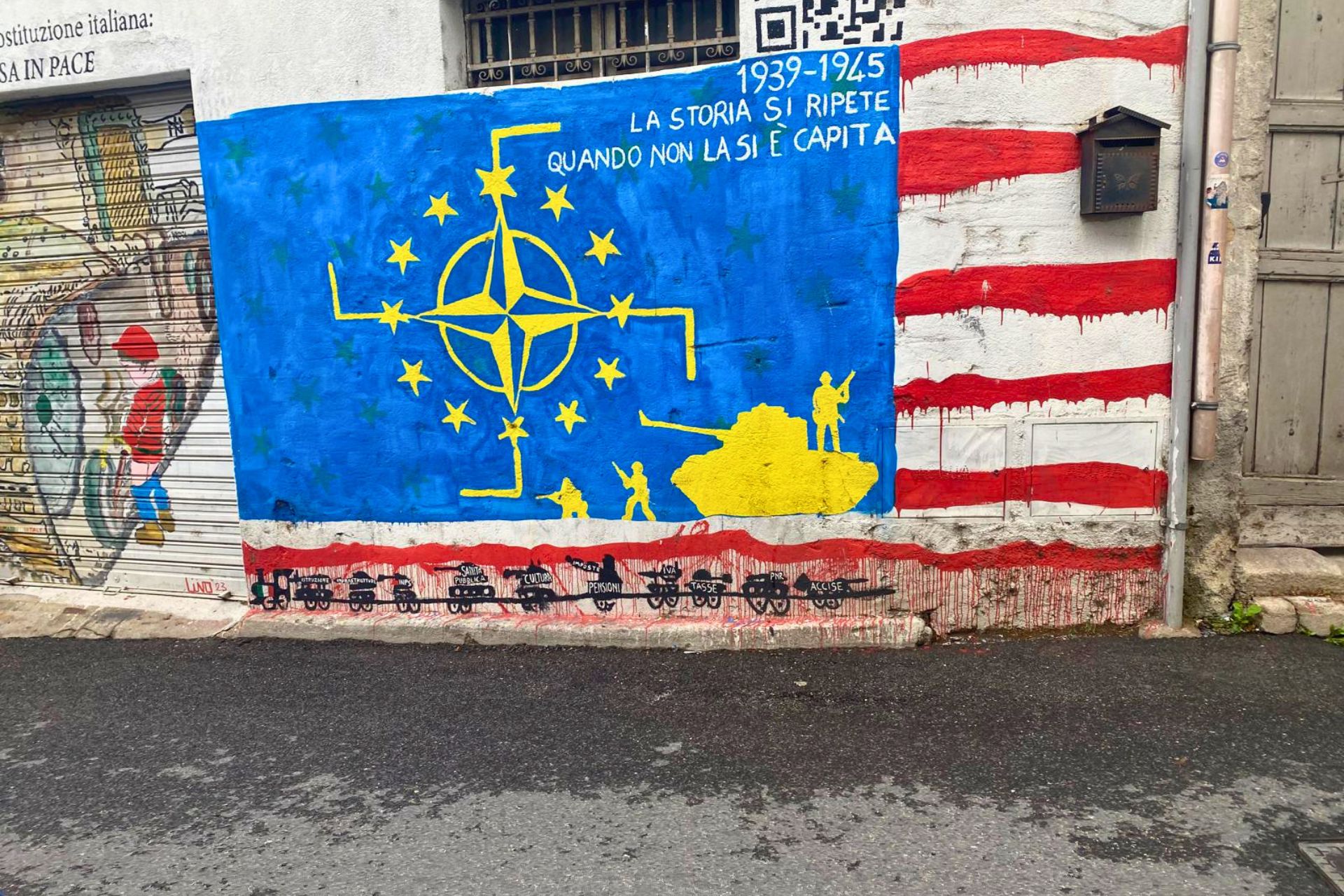 Mur avec des peintures murales représentant des drapeaux et des symboles politiques, écrites en italien
