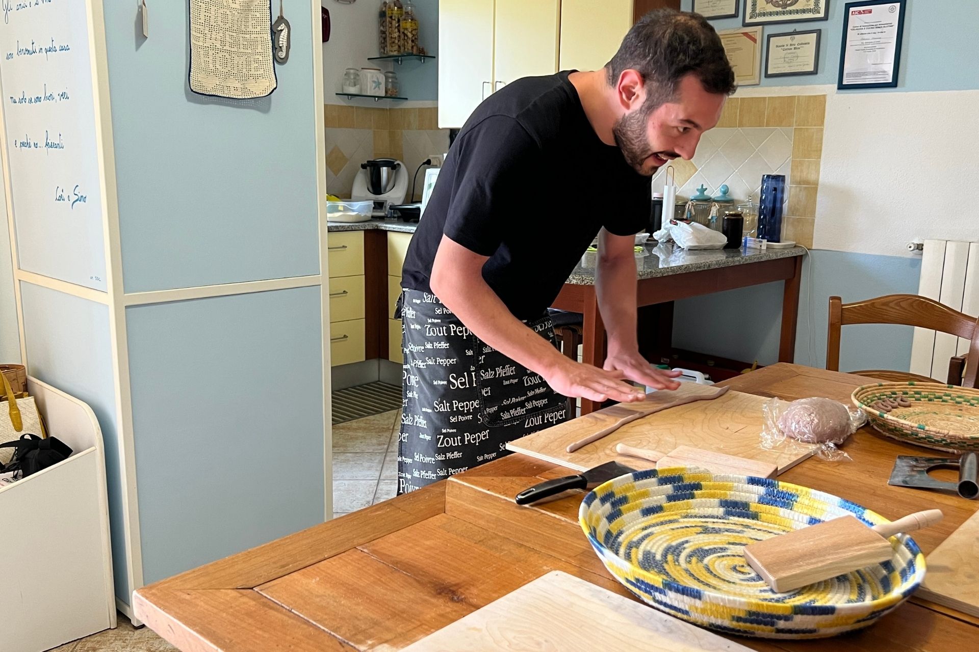 Man preparing fresh pasta on a kitchen table with typical Sardinian ingredients and tools.