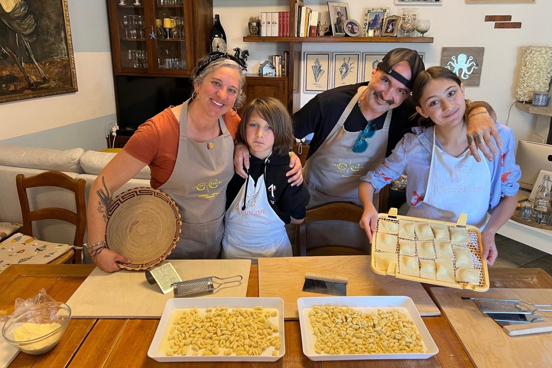 A family with two children takes part in a fresh Sardinian pasta workshop in Arzachena, in the heart of Gallura. You can see the children holding plates with pasta in their hands, and an adult holding a grater.