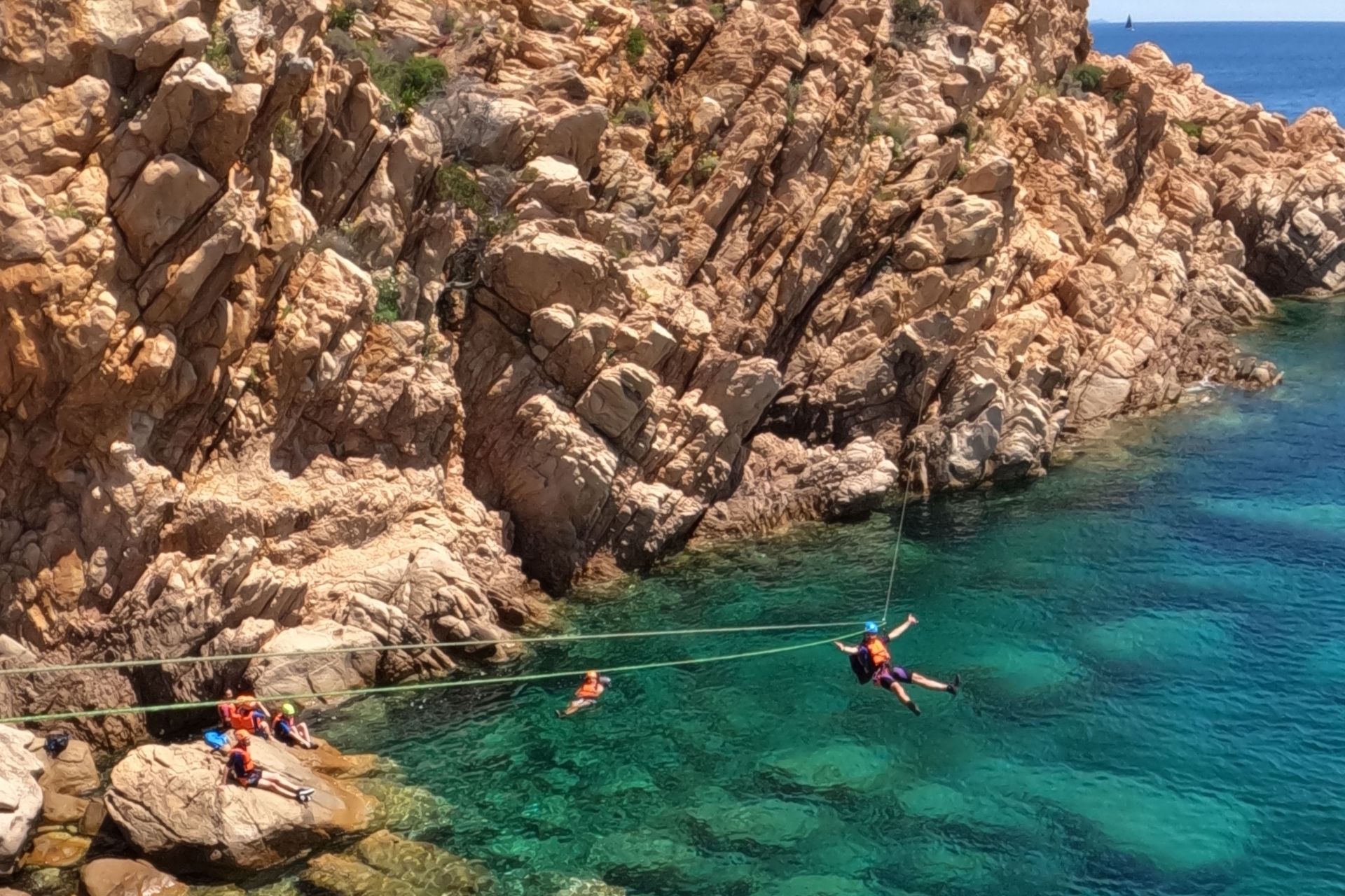 Persone che si avventurano in coasteering lungo una costa rocciosa con il mare sottostante