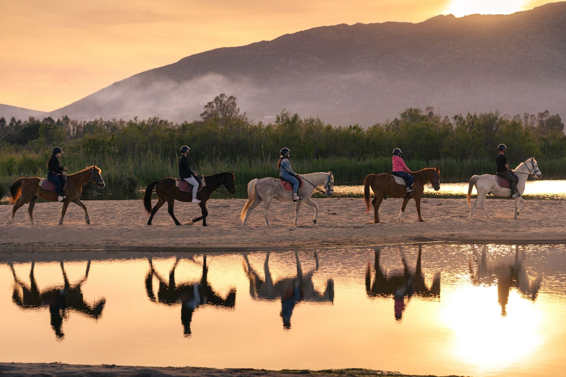 Horseback ride on the beach of Orosei at sunset, at the mouth of the Cedrino river.