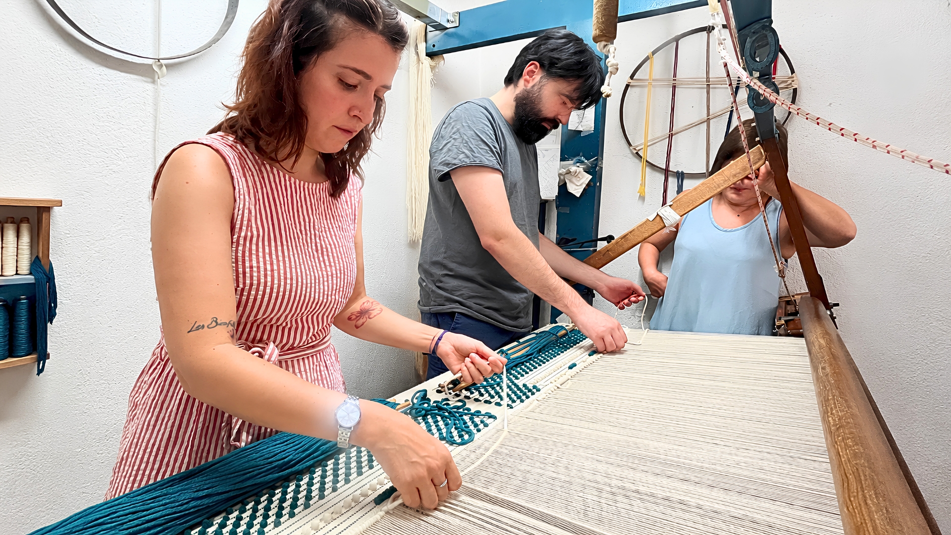 Gruppo di persone che lavorano su un telaio di tessitura con filo colorato