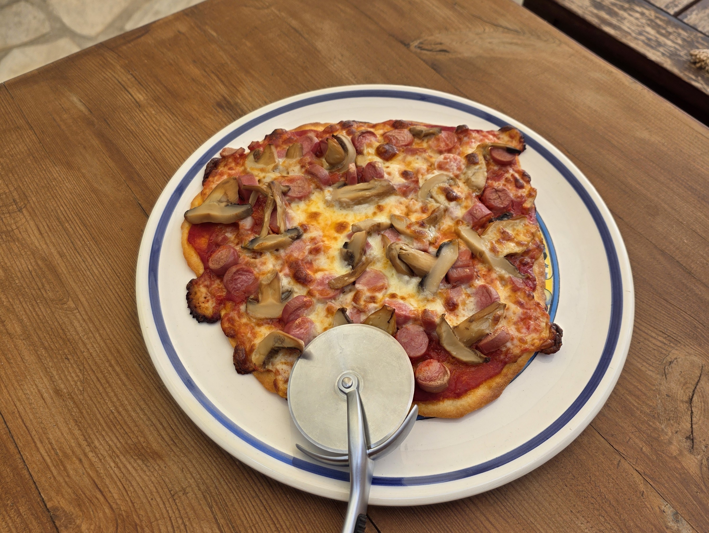A freshly baked pizza with sausage and mushrooms, ready to be enjoyed after the workshop