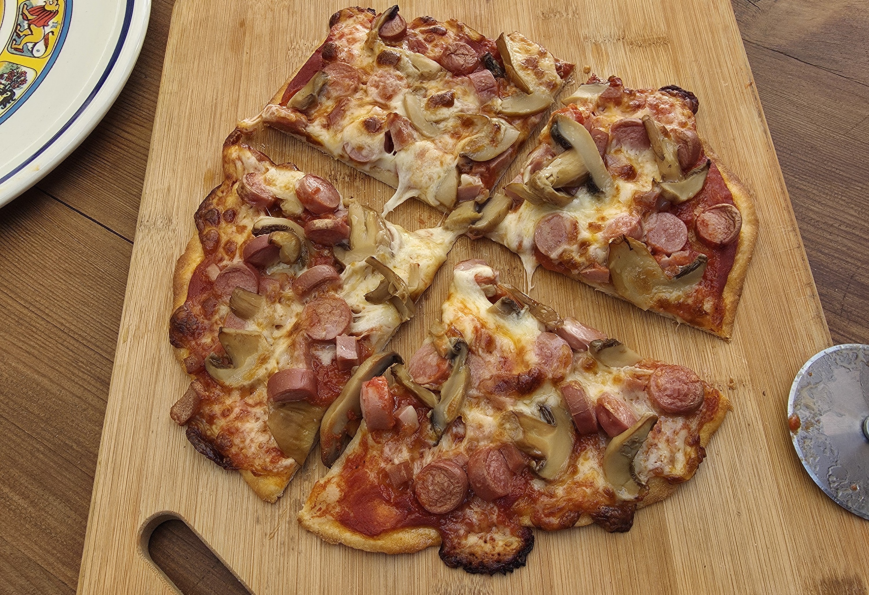 Pizza with sausage and mushrooms on a wooden cutting board ready to be enjoyed
