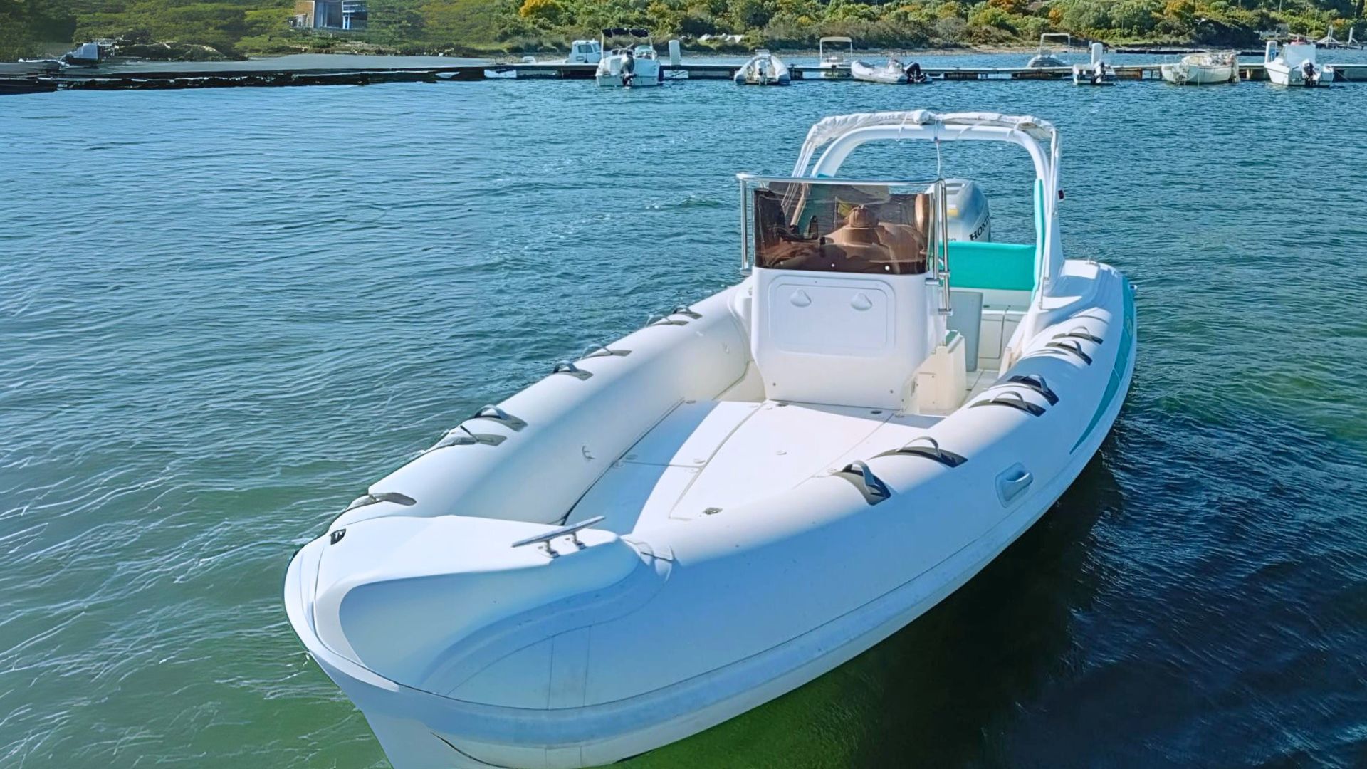 Ein Beiboot segelt im Wasser in der Nähe eines Strandes und einer Küste mit einem Pier