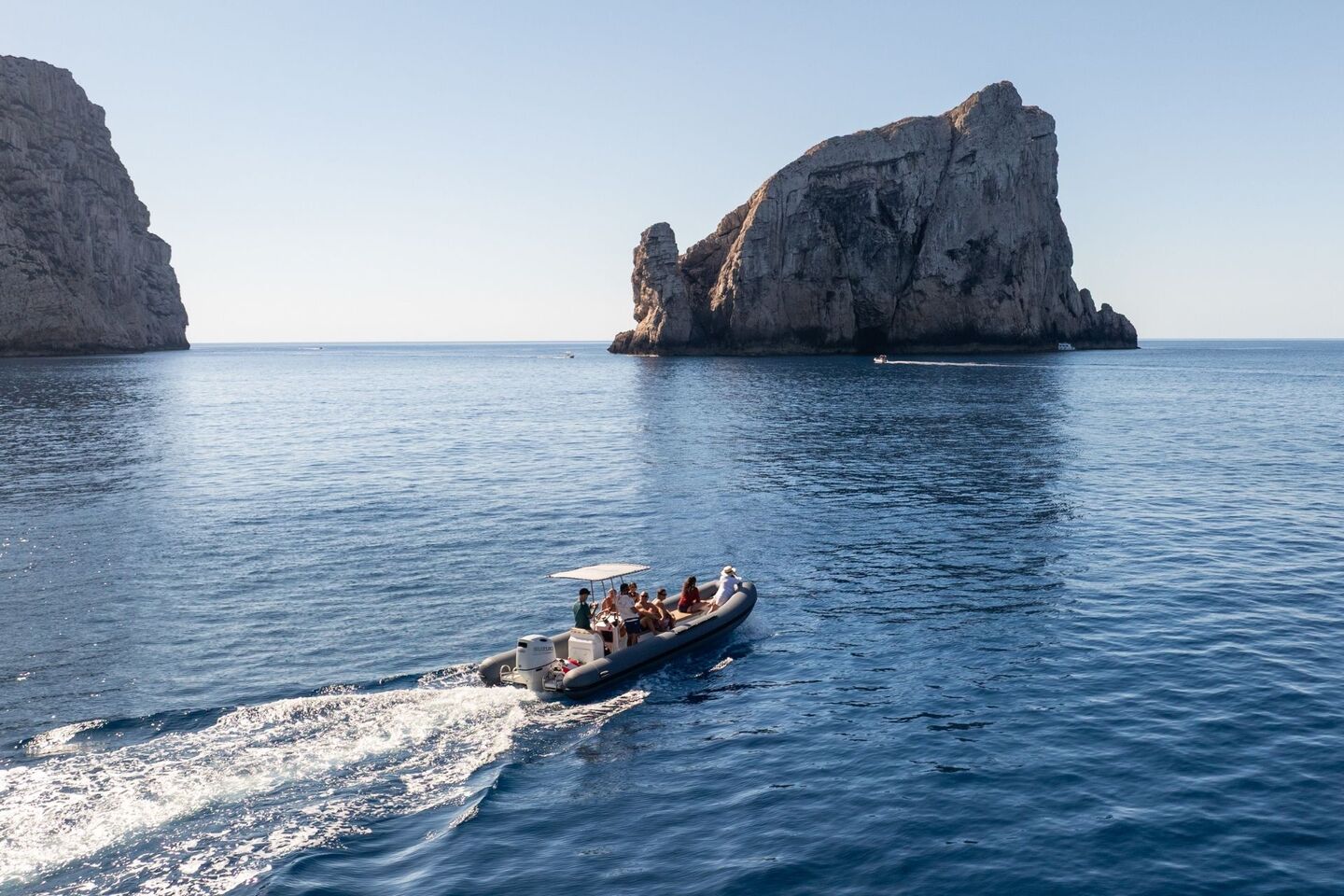 The dinghy moves to the Faraglione di Foradada in Capo Caccia, Alghero