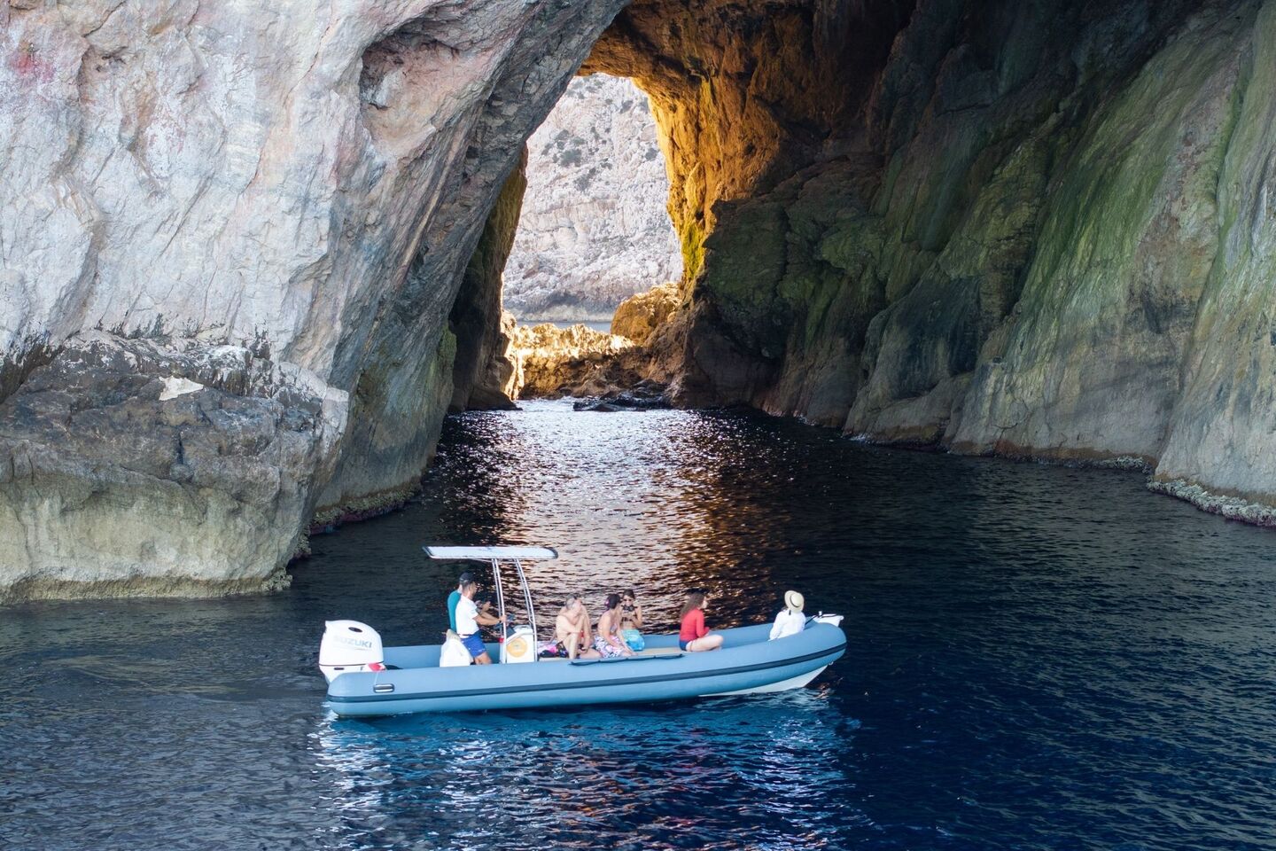 The dinghy goes into the cave of Faraglione di Foradada in Capo Caccia, Alghero